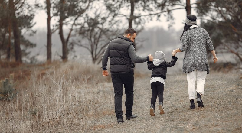 Family with cute little child. Father in a black jacket. People have fun in a spring forest